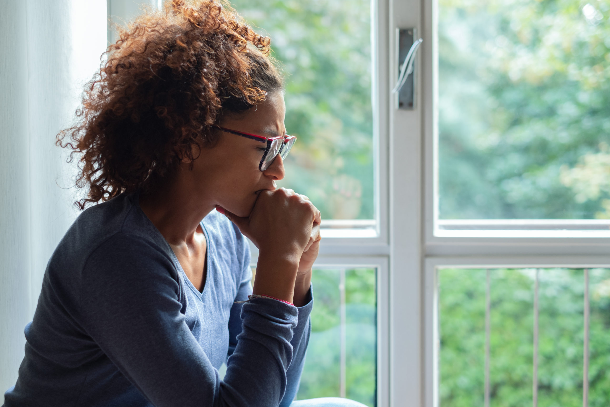 Lonely black woman near window thinking about something